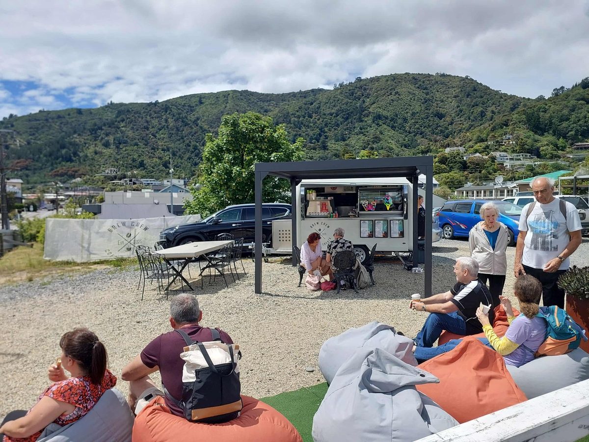 Brew Crew food trailer and outdoor seating beneath a pergola, with the Picton hills behind.