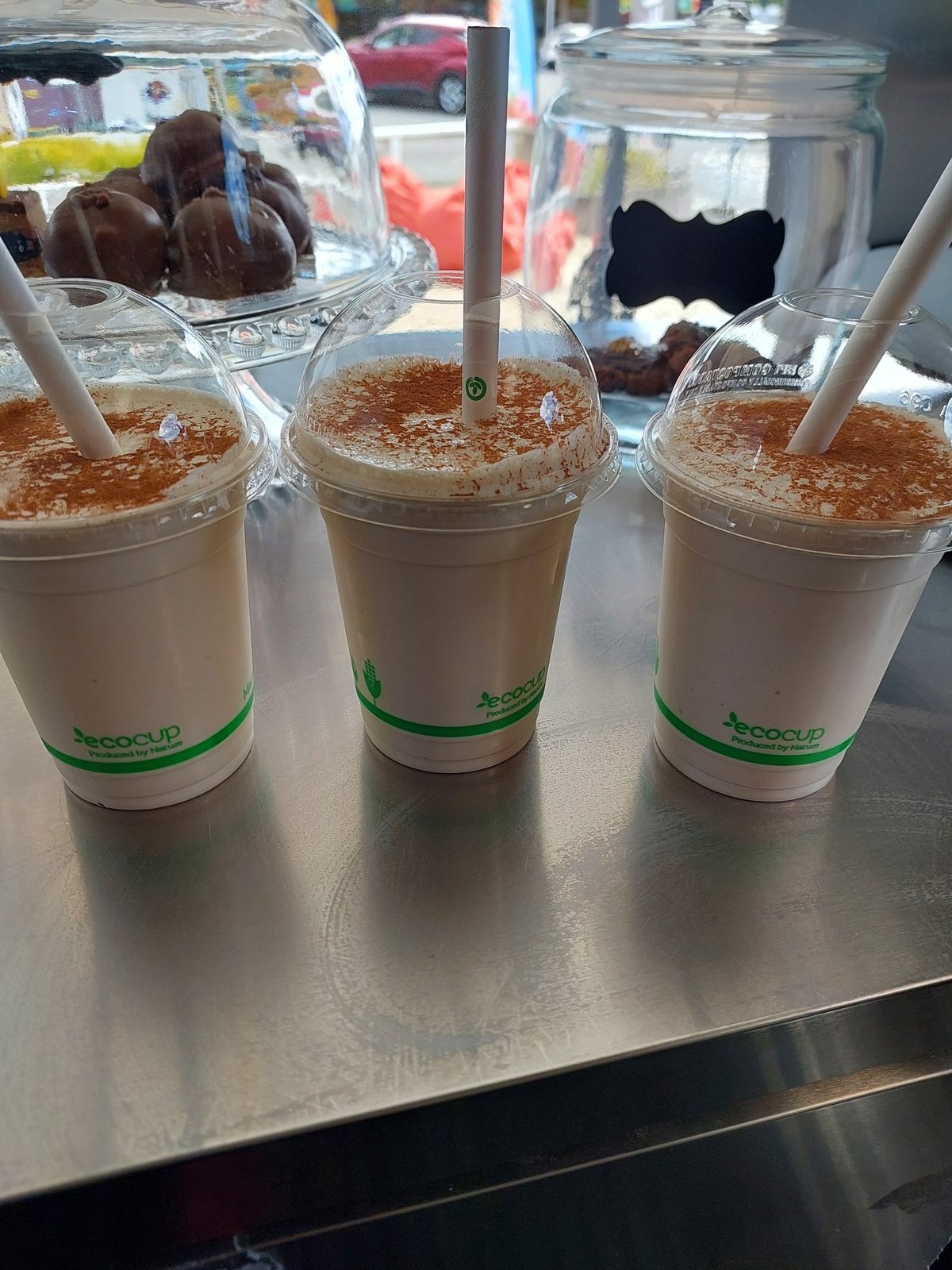Three cinnamon-dusted milkshakes on the trailer counter, with cabinet treats visible behind.