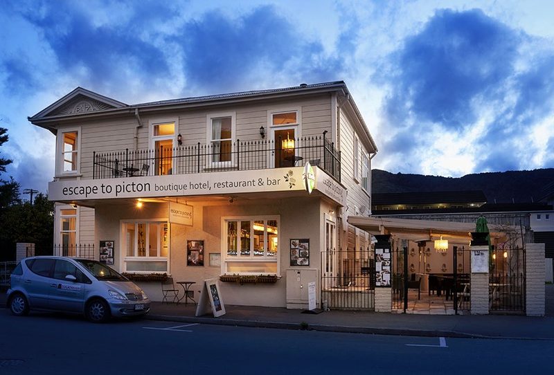 Street-facing exterior of the boutique hotel, restaurant and bar at dusk, with its name across the facade.