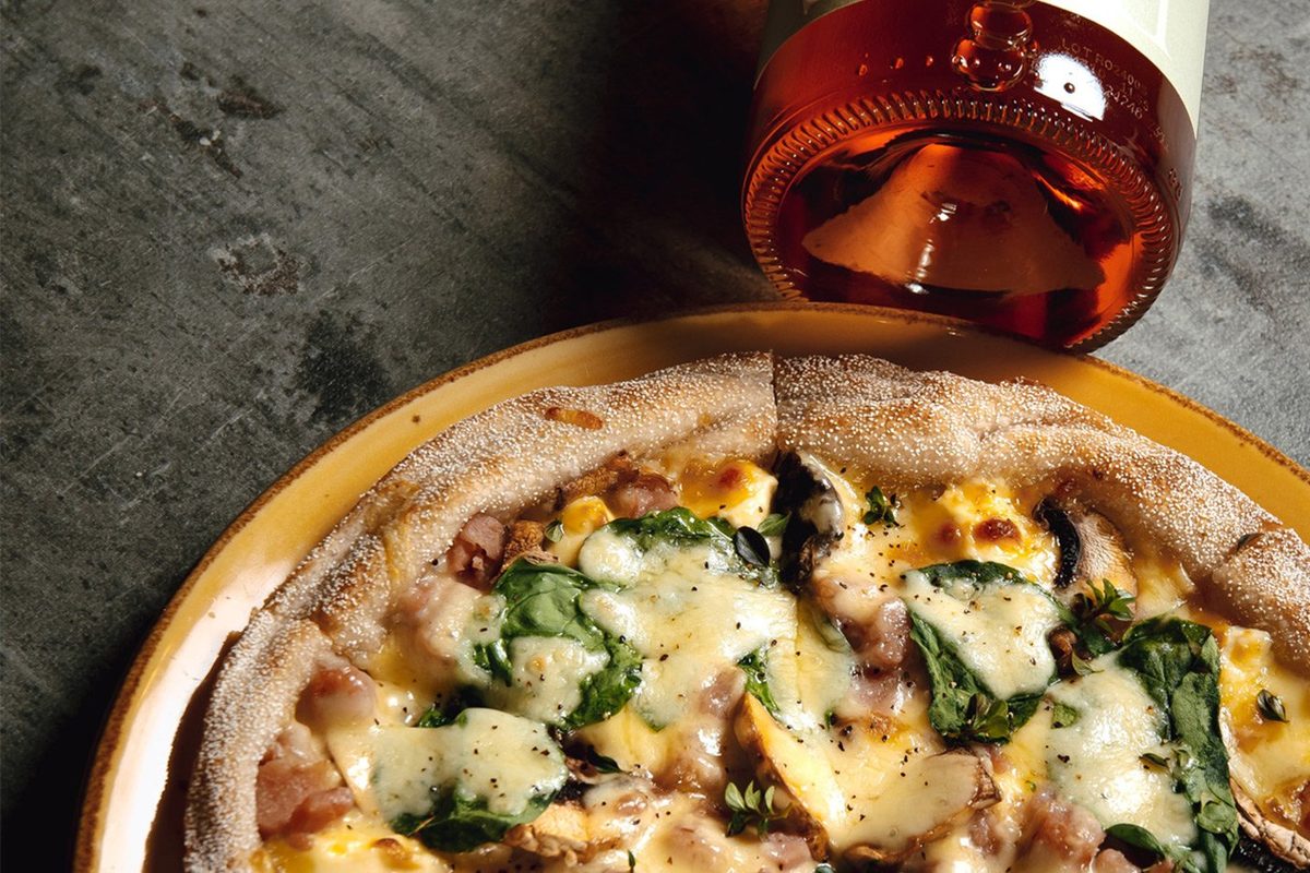 Fork & Fable pizza topped with mushrooms, greens and cheese beside a bottle of rosé.