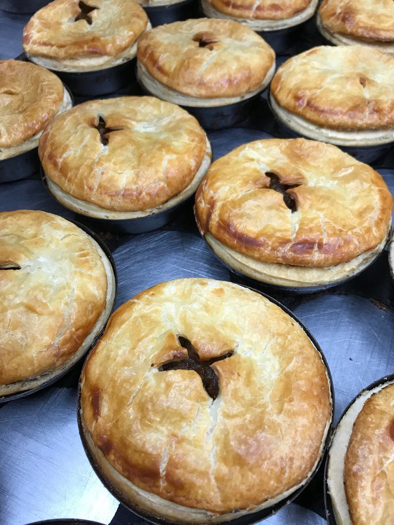 Close-up of freshly baked golden pies in individual tins.