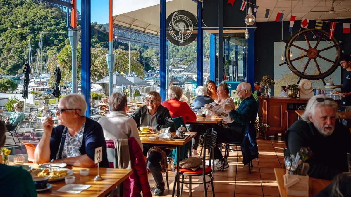 Bright nautical-themed dining room with occupied tables and Picton marina visible through the windows.