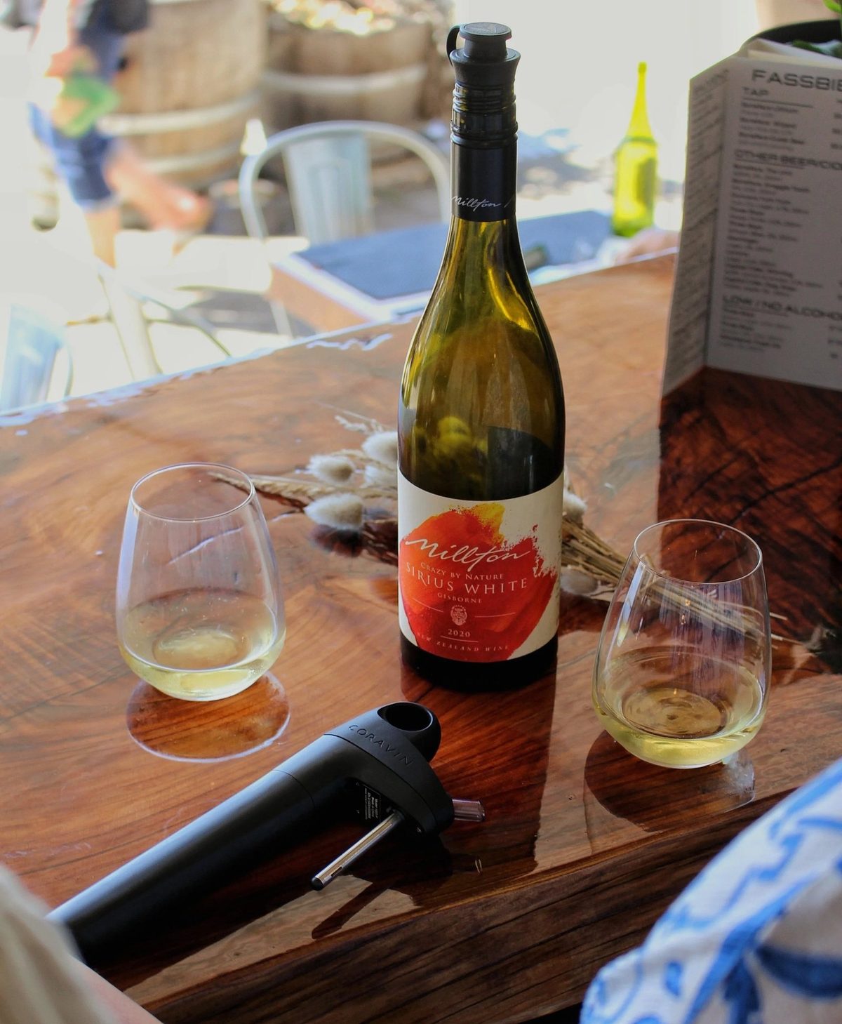 A bottle of Millton Sirius White and two glasses on Sisu's wooden table.
