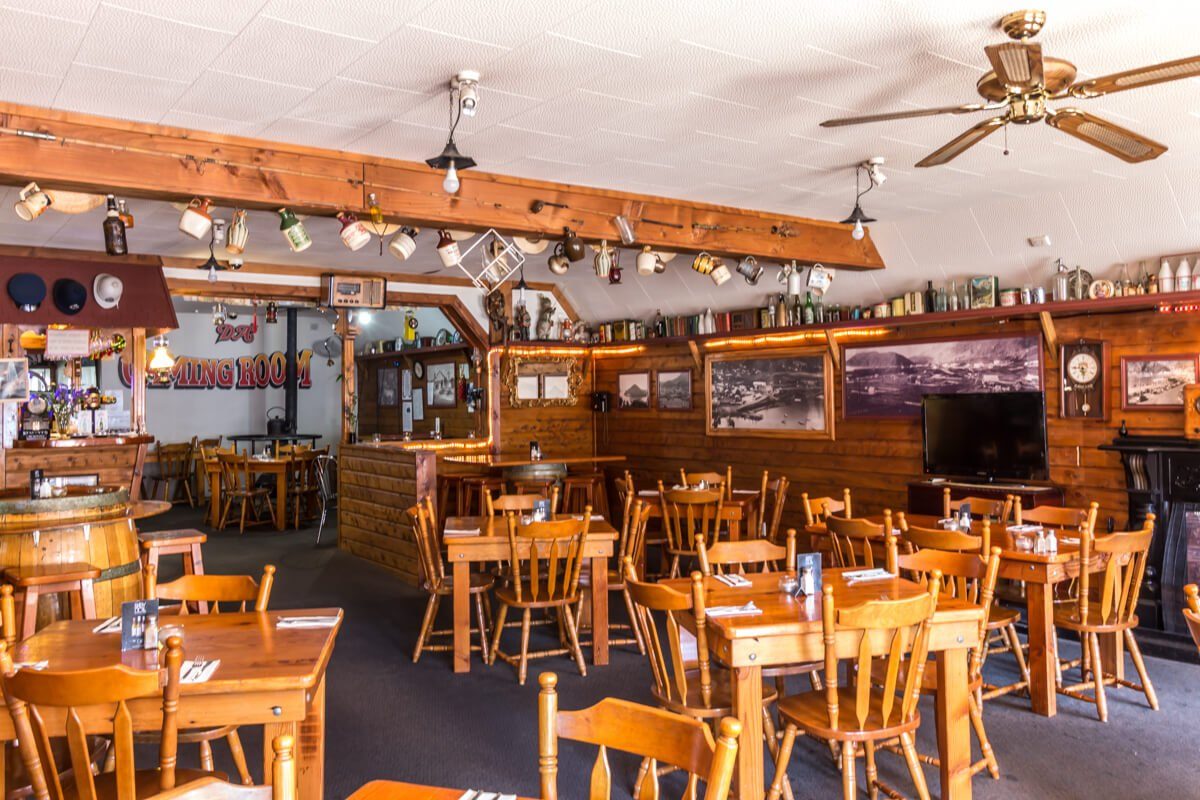 Wood-lined main dining room with set tables, barrel decor, historic photographs and bar area.